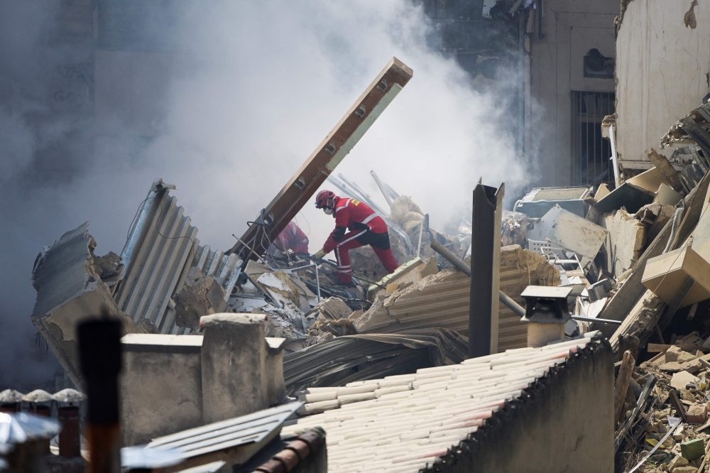 Firefighter work on rubble at the 'rue Tivoli' after a building collapsed in the same street, in Marseille, southern France, on April 9, 2023. (Photo by CLEMENT MAHOUDEAU / AFP)