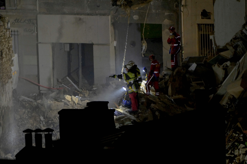 Emergency service personnel look into the rubble at 'rue Tivoli' after a building collapsed in the street, in Marseille, southern France, on April 9, 2023. (Photo by Clement Mahoudeau / AFP)