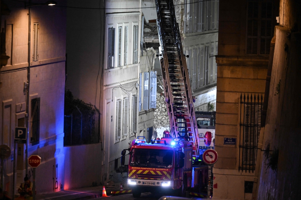 A firetruck extends a ladder at the scene of a collapsed building on 'rue Tivoli', in Marseille, southern France, on April 10, 2023. (Photo by Nicolas Tucat / AFP)