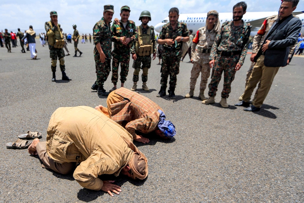 Returned Houthi prisoners exchanged in a deal Yemen's internationally recognised-government prostrate in prayer on the tarmac upon arrival at Sanaa International Airport on April 14, 2023. (Photo by MOHAMMED HUWAIS / AFP)
