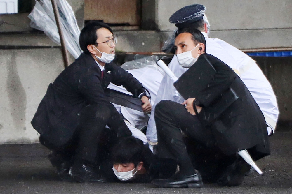 A man (bottom) is detained after throwing an apparent 