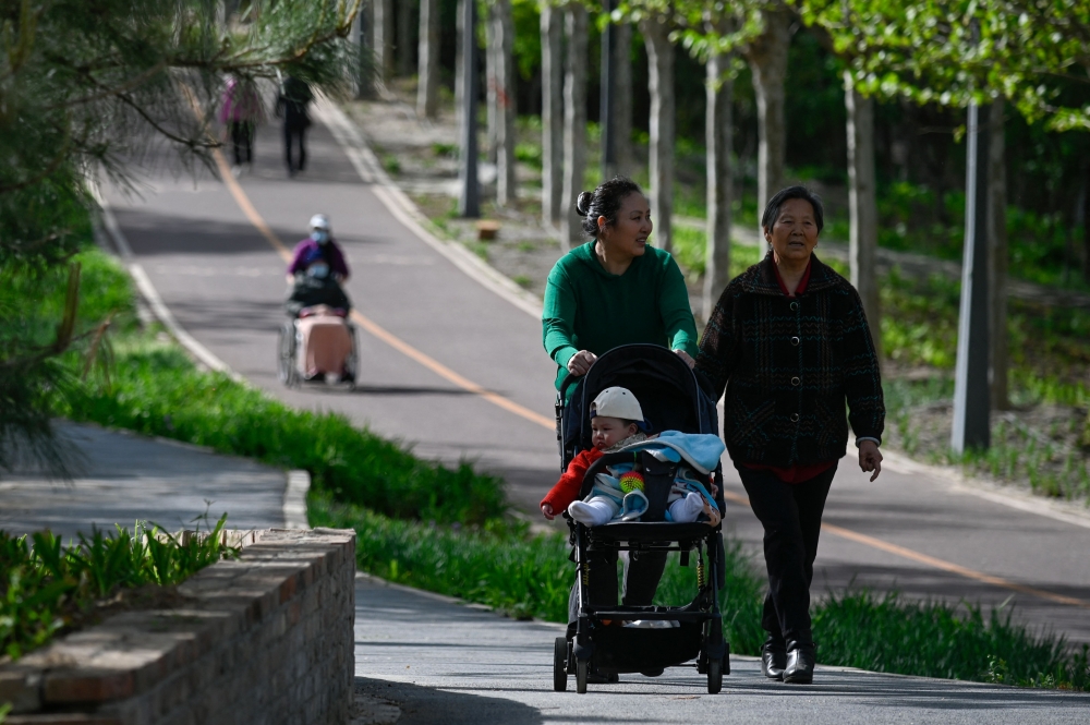 People walk in a public park in Beijing on April 15, 2023. Photo by WANG Zhao / AFP