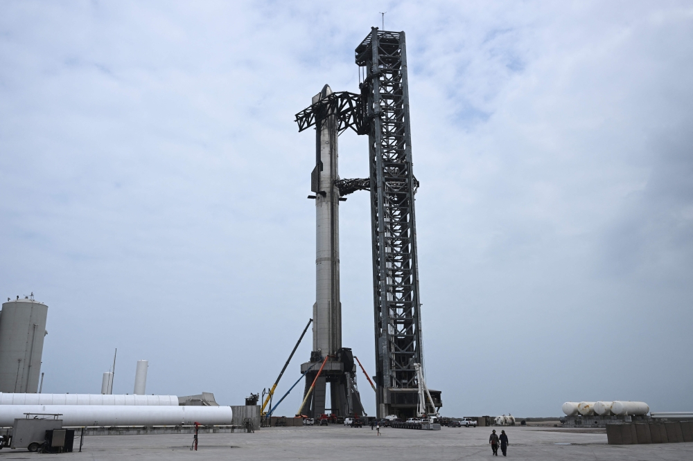 Workers in lifts prepare the SpaceX Starship ahead of the scheduled launch from the SpaceX Starbase in Boca Chica, Texas on April 19, 2023. Photo by Patrick T. Fallon / AFP