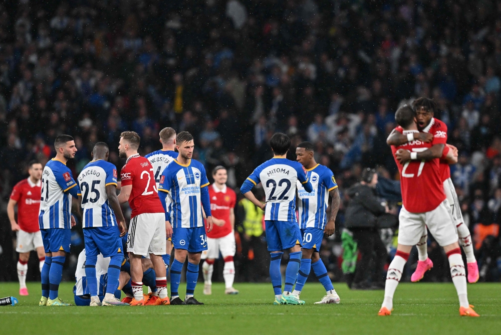 Manchester United's English defender Luke Shaw (C) commiserates Brighton players after Manchester United won a penalty shoot out during the English FA Cup semi-final football match between Manchester United and Brighton and Hove Albion at Wembley Stadium in north west London on April 23, 2023. (Photo by Glyn KIRK / AFP) 
