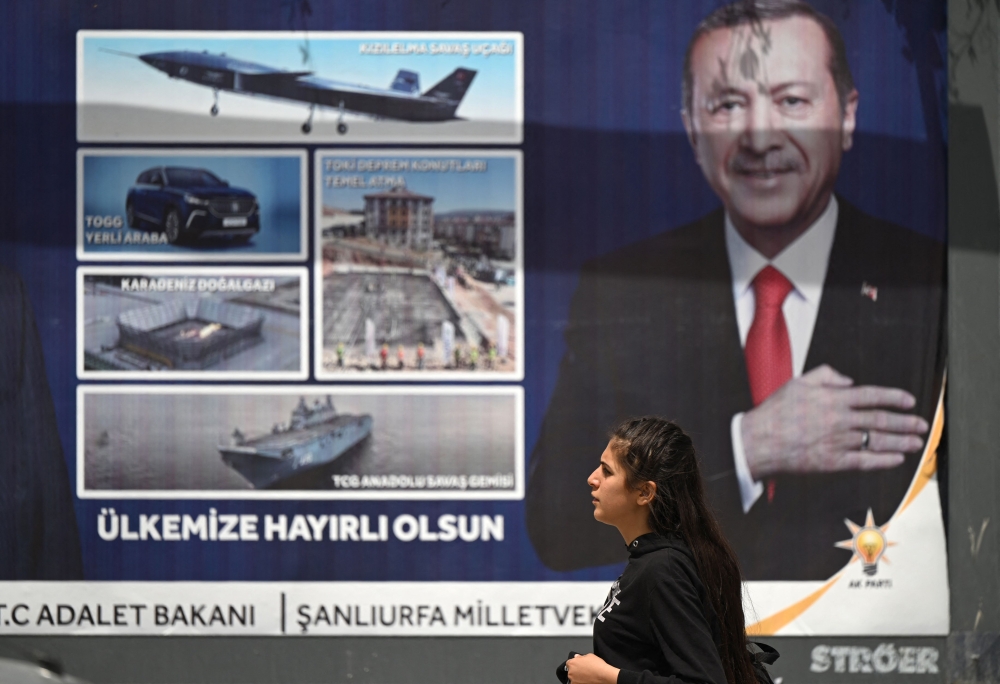 A woman walks past a billboard with the portrait of Turkish President Recep Tayyip Erdogan in Sanliurfa, south-eastern Turkey on April 28, 2023. (Photo by OZAN KOSE / AFP)