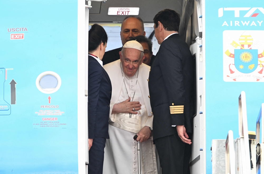 Pope Francis waves bords the plane following the farewell ceremony at Budapest International Airport on April 30, 2023 as his second visit to Hungary in less than two years comes to an end. (Photo by Attila KISBENEDEK / AFP)