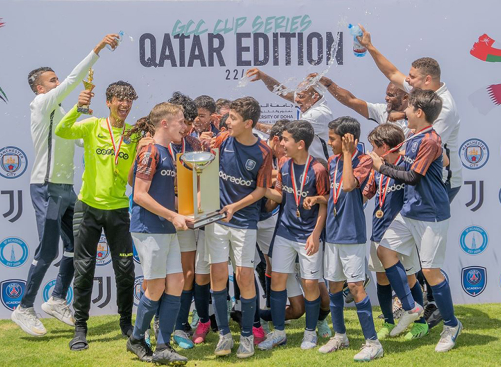 Paris Saint Germain Academy Qatar players and officials celebrate with the GCC Cup trophy.

