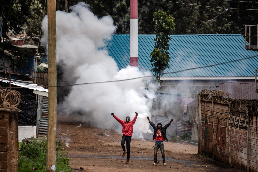 Opposition supporters react after a teargas canister was shot by Kenyan police officers during riots in the informal settlement of Kibera in Nairobi on May 2, 2023. (Photo by Luis Tato / AFP)