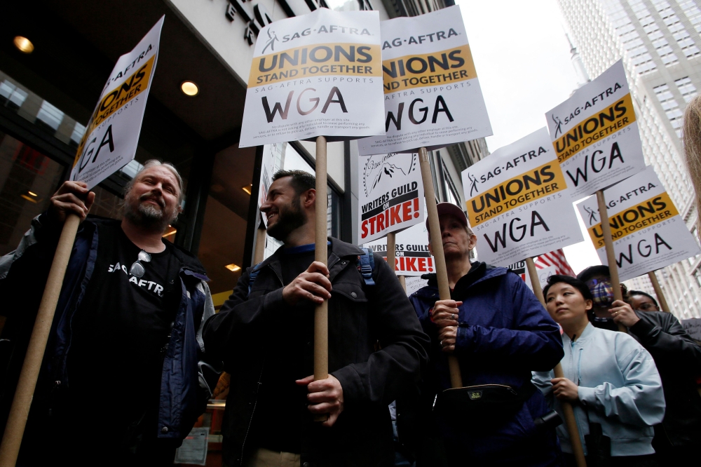 Demonstrators carry signs during a screenwriter's strike in New York City on May 2, 2023. (Photo by Leonardo Munoz / AFP)
