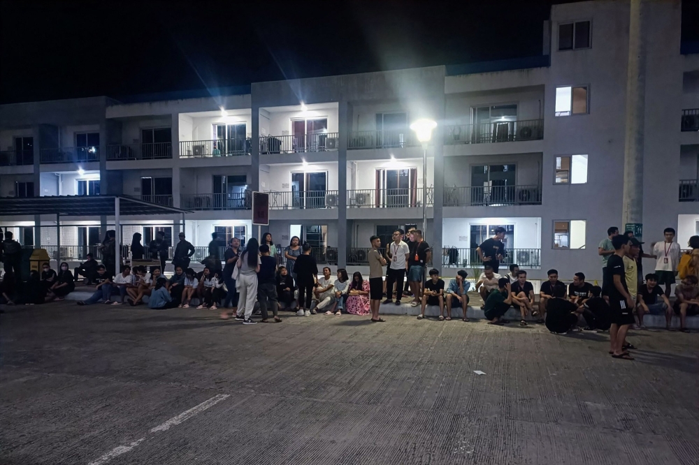 This handout photo taken on May 4, 2023 and received from the Philippine National Police anti-Cybercrime group on May 6 shows rescued trafficked people from Asian countries standing outside a building after a police raid inside a freeport zone in Mabalacat City, in Pampanga province, north of Manila. (Photo by Handout / Philippine National Police Anti-Cybercrime Group / AFP)