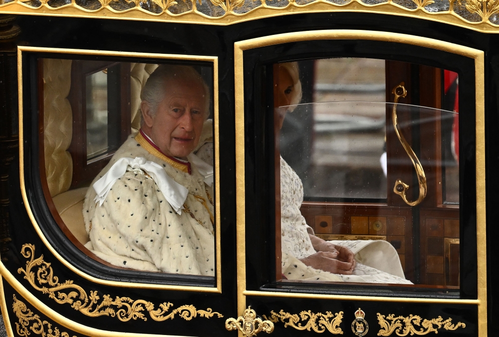 Britain's King Charles III and Britain's Camilla, Queen Consort begin their journey in the Diamond Jubilee State Coach (Photo by Marco BERTORELLO / AFP)