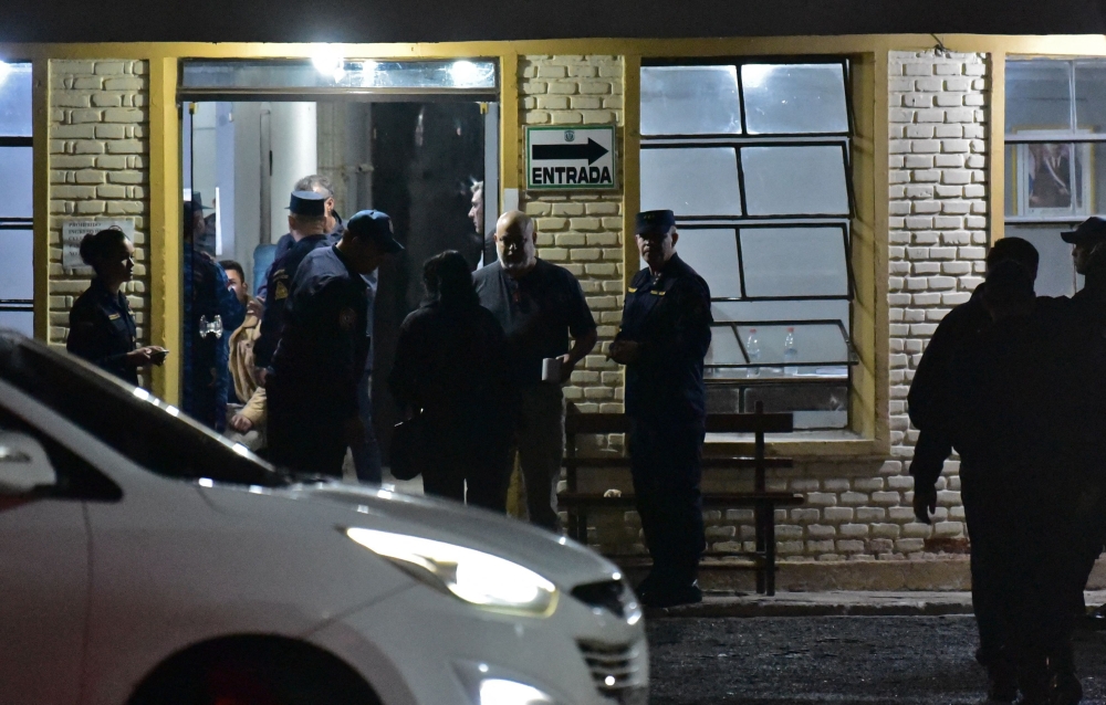 Paraguay's ex-presidential candidate for the Partido Cruzada Nacional political party, Paraguayo Cubas (C), is surrounded by police officers at the entrance of a station of the Police's Specialized Group in Asuncion, after being preventively detained on charges of disturbing public peace, on May 5, 2023. (Photo by Norberto DUARTE / AFP)
