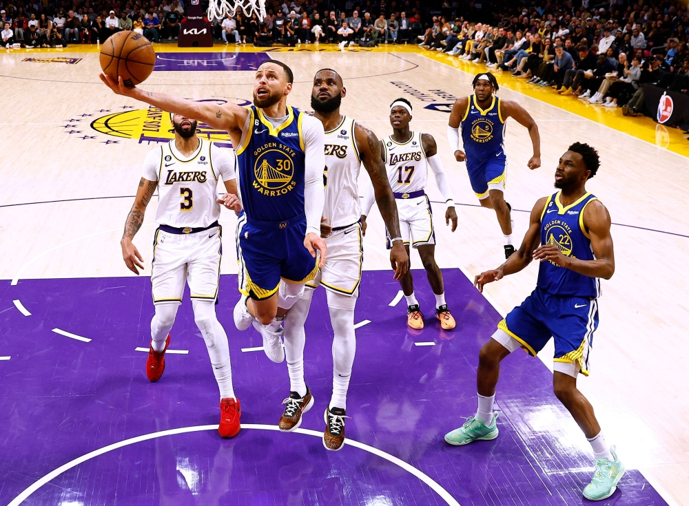 Stephen Curry #30 of the Golden State Warriors scores on a layup in front of LeBron James #6 of the Los Angeles Lakers. Ronald Martinez/Getty Images/AFP