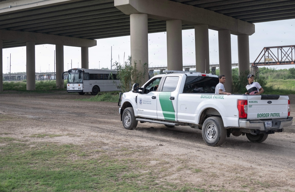 Two migrants are transported by US Customs and Border Patrol, under a bridge that connects the US and Mexico, in Eagle Pass, Texas, on May 10, 2023.  (Photo by ANDREW CABALLERO-REYNOLDS / AFP)

