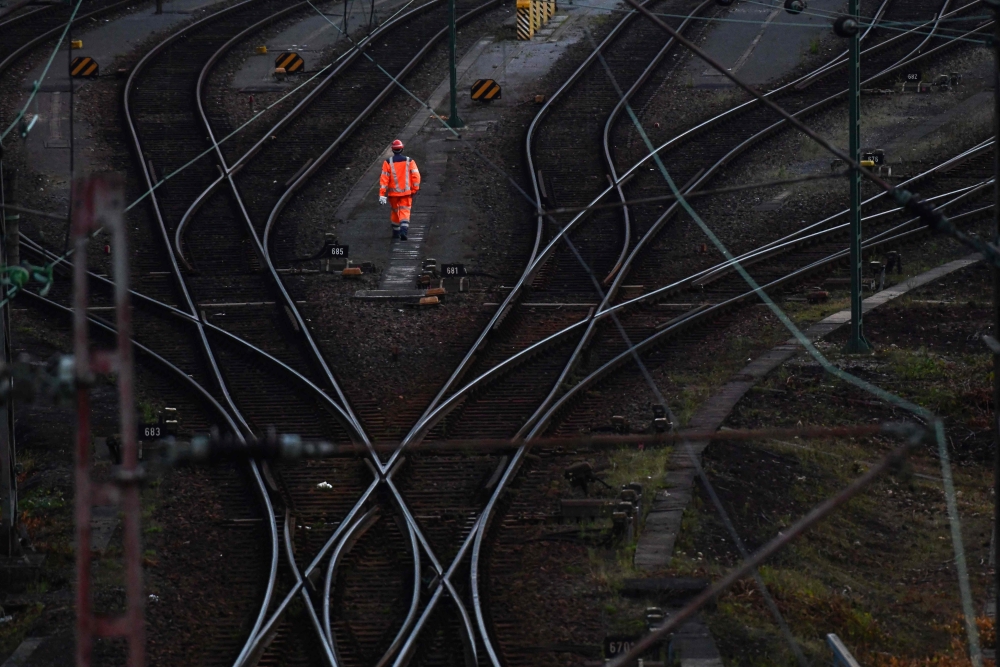 This file photo taken on August 12, 2021 shows a worker walking next to the rails at a transshipment point for freight trains in Hagen, western Germany, as Deutsche Bahn employees went on strike over wages. Photo by Ina FASSBENDER / AFP