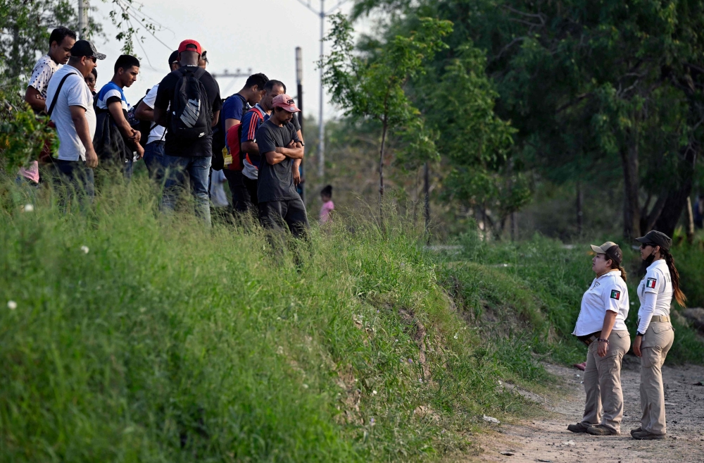 Members of the Beta Group of the Mexican Government (R) instruct migrants not to cross the Rio Bravo river (Rio Grande in the US) into the US, in the border city of Matamoros, Tamaulipas State, Mexico, on May 10, 2023. (Photo by Alfredo ESTRELLA / AFP)