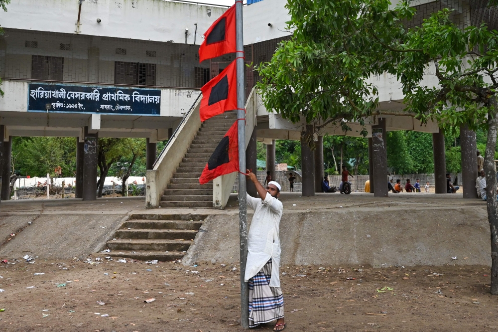 A man raises a storm danger signal flag in Teknaf on May 13, 2023, ahead of Cyclone Mocha's landfall. (Photo by Munir uz zaman / AFP)