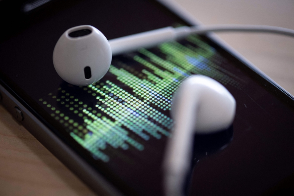 A picture taken on February 8, 2019 in Paris shows a smartphone and its earphones as an audio podcast is being played. Photo by Thomas SAMSON / AFP