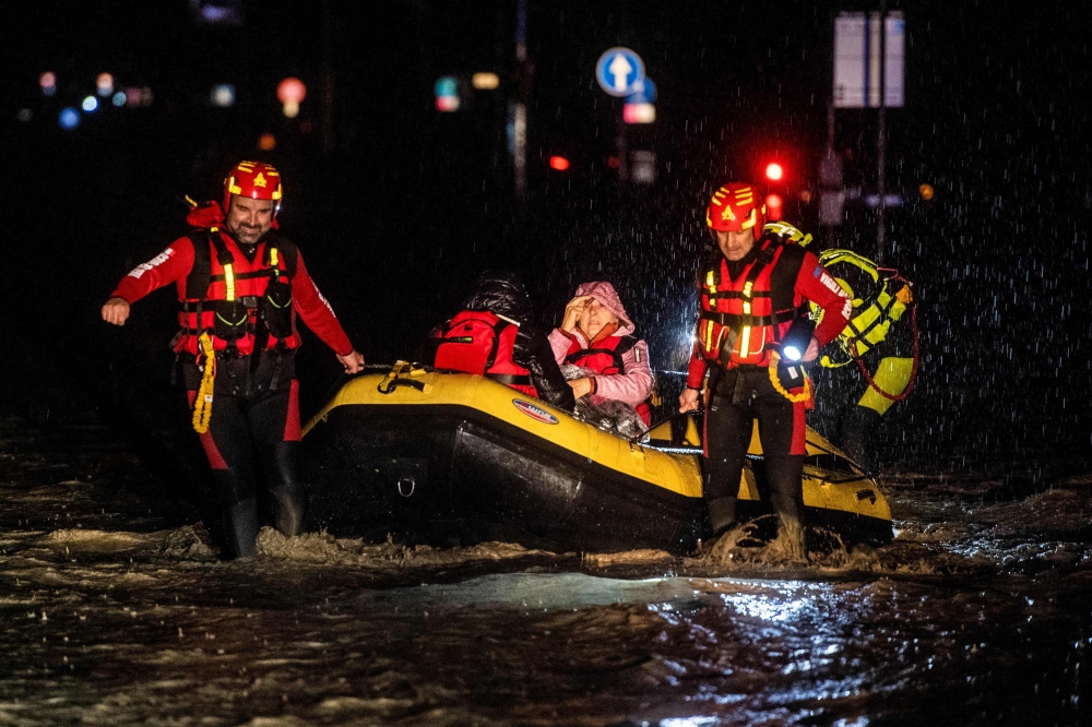 Firemen and civil protection rescuers evacuate a woman with an inflatable boat in Forli on May 17, 2023 after heavy rains have caused major floodings in central Italy, where trains were stopped and schools were closed in many towns while people were asked to leave the ground floors of their homes and to avoid going out. Photo by AFP