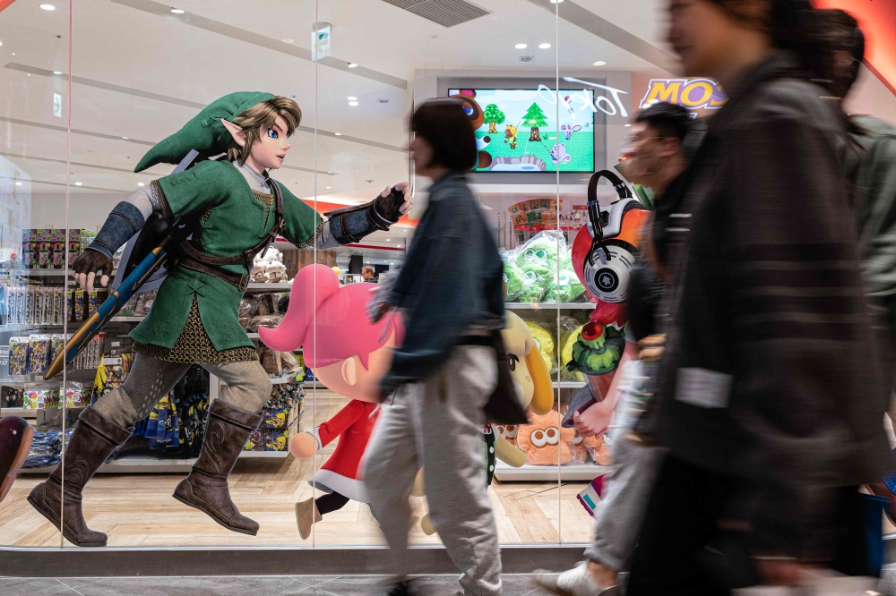 This photo taken on May 8, 2023 shows people walking past an illustration for Japanese gaming giant Nintendo's long-running 'Legend of Zelda' game series, in the window of the company's official store in Tokyo's Shibuya district. (Photo by Richard A. Brooks / AFP)