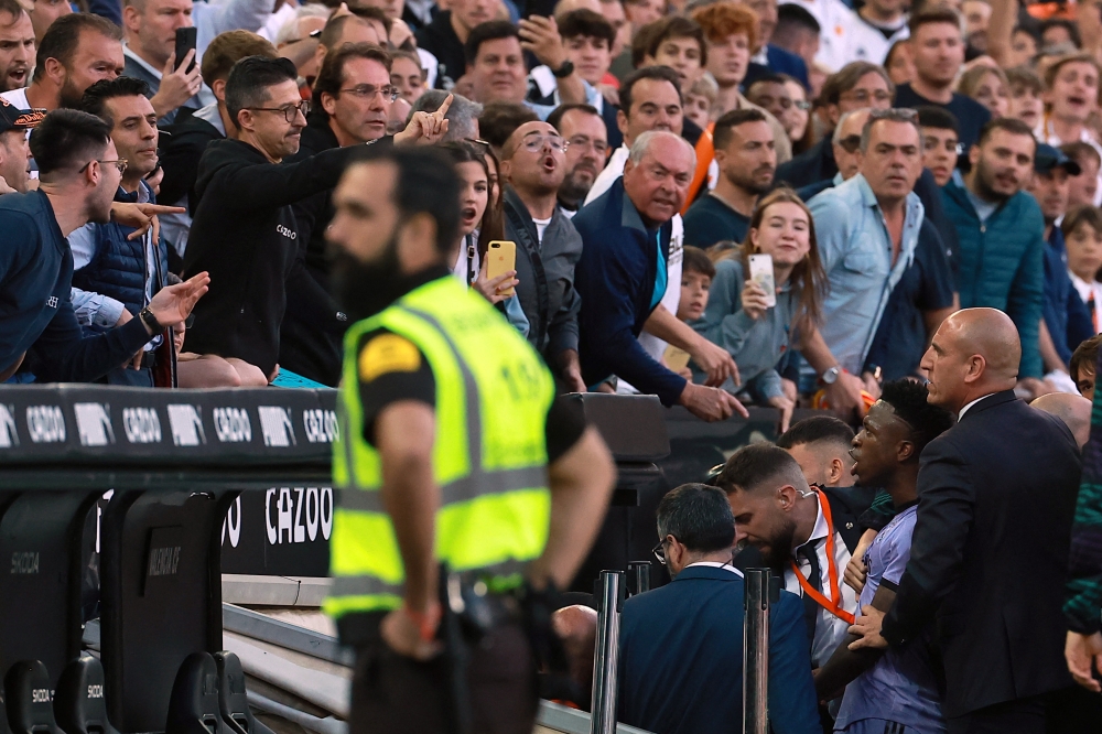Real Madrid's Brazilian forward Vinicius Junior (R) confronts the public as he leaves after being sent off the pitch by the referee during the Spanish league football match between Valencia CF and Real Madrid CF at the Mestalla stadium in Valencia on May 21, 2023. (Photo by JOSE JORDAN / AFP)