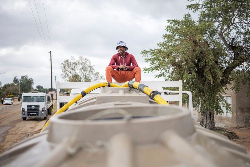 A man sits on top of a municipal tank truck while filling it with water in Hammanskraal on May 23, 2023. (Photo by Michele Spatari / AFP)