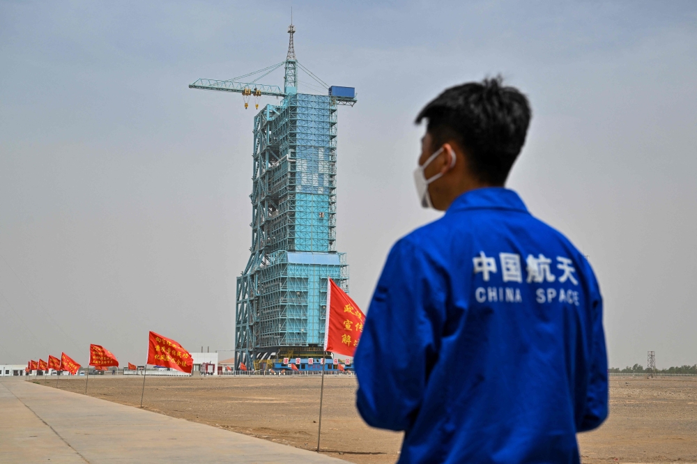 A staff member from the China space program stands before the launch platform of the Shenzhou-16 Manned Space Flight Mission one day before launch at the Jiuquan Satellite Launch Centre in China's northwestern Gansu province on May 29, 2023. Photo by Hector RETAMAL / AFP