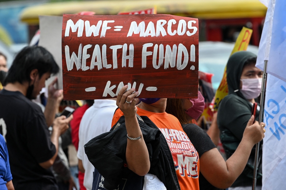 A protester holds a placard during a rally in front of the House of Representatives in Quezon City on December 12, 2022, as legislators deliberate on the sovereign wealth fund proposed law. (Photo by Ted Aljibe / AFP)
