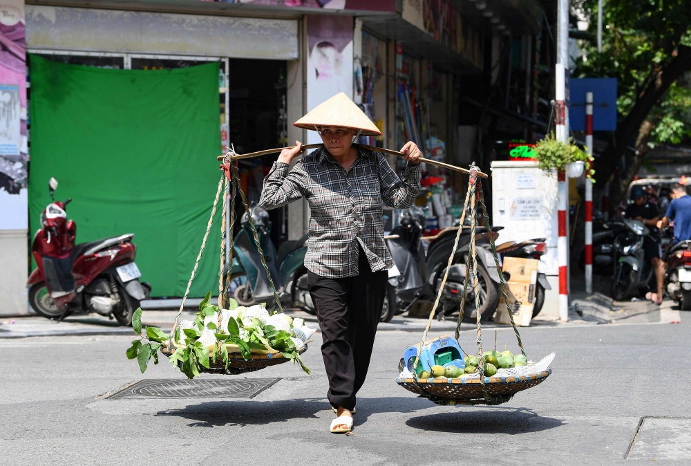 A street vendor carries mangoes in Hanoi on June 1, 2023. (Photo by Nhac Nguyen / AFP) 
