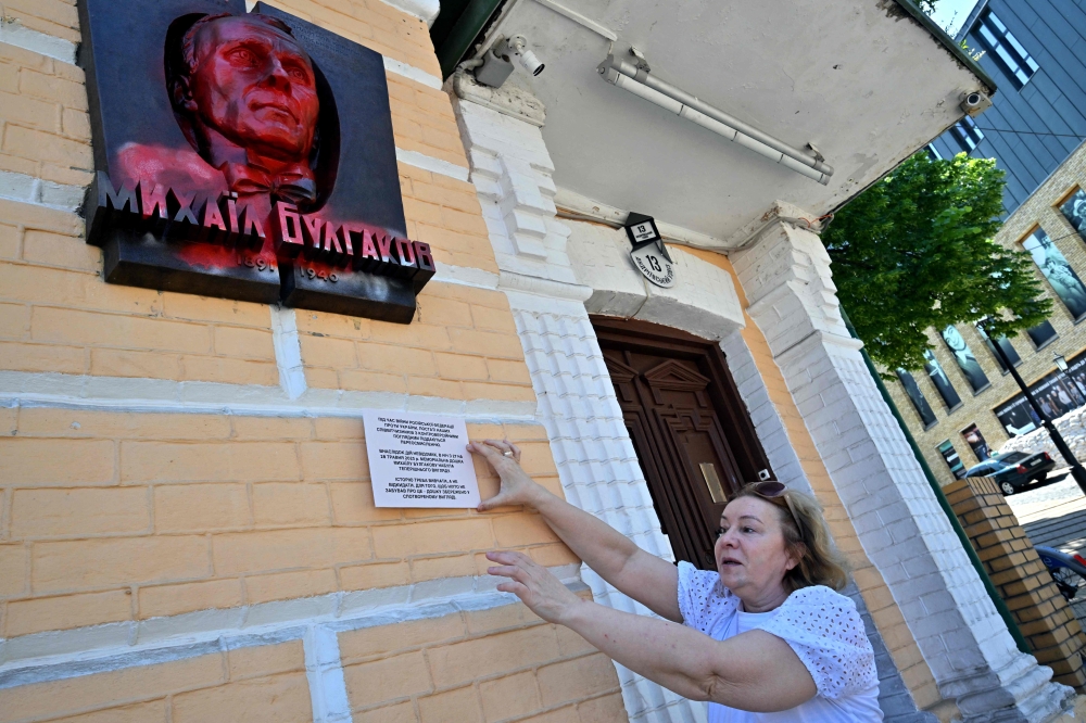 The museum's director Lyudmyla Gubianuri shows the plaque depicting Mikhail Bulgakov, the author of 