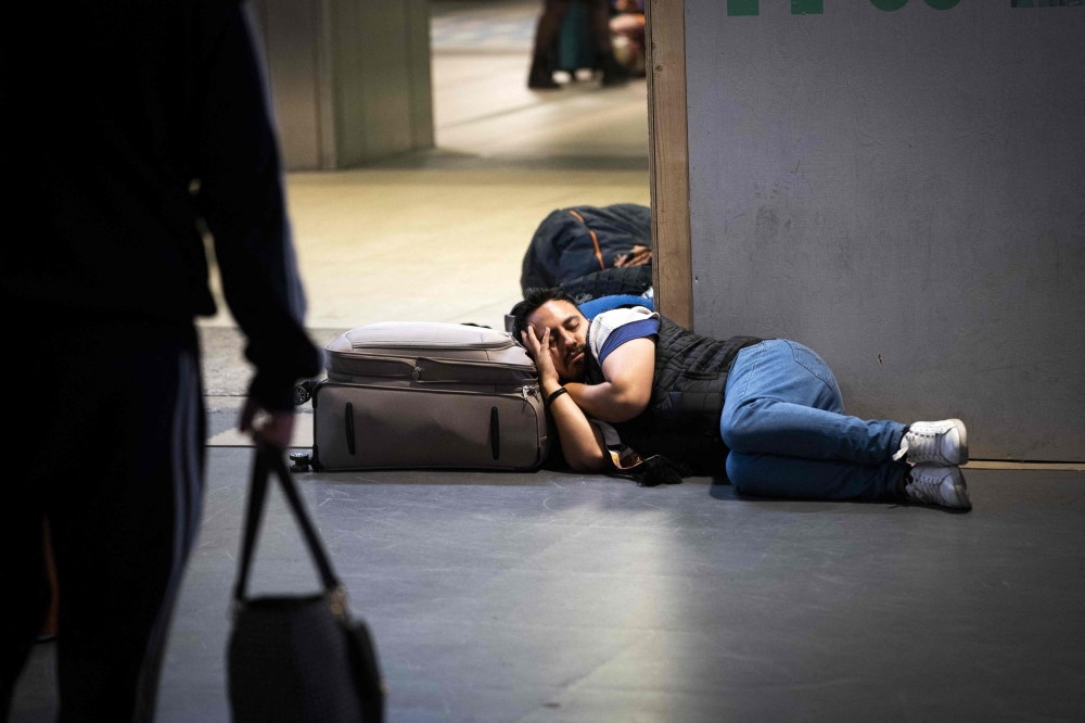 A travelers lies on the ground as he waits for a train after the traffic was stopped at Central rail station in Amsterdam on June 5, 2023. Photo by Koen LAUREIJ / ANP / AFP