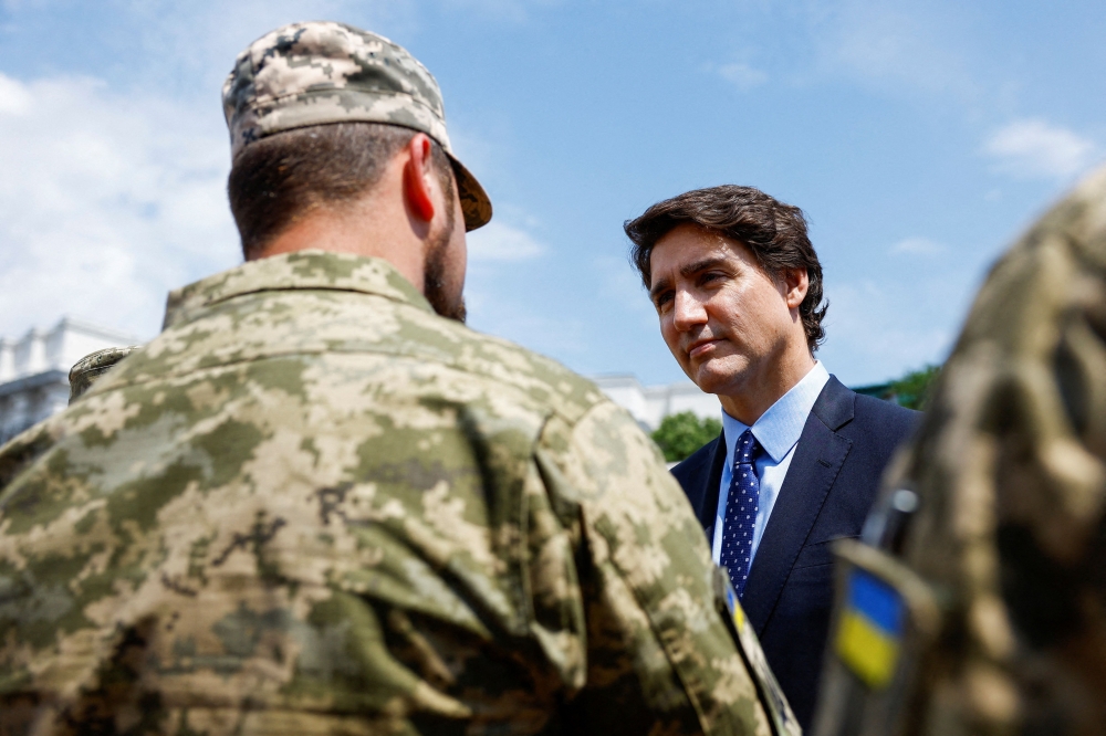 Canadian Prime Minister Justin Trudeau speaks with Ukrainian soldiers as he visits an exhibition of destroyed military vehicles in Kyiv on June 10, 2023. (Photo by Valentyn Ogirenko / AFP)