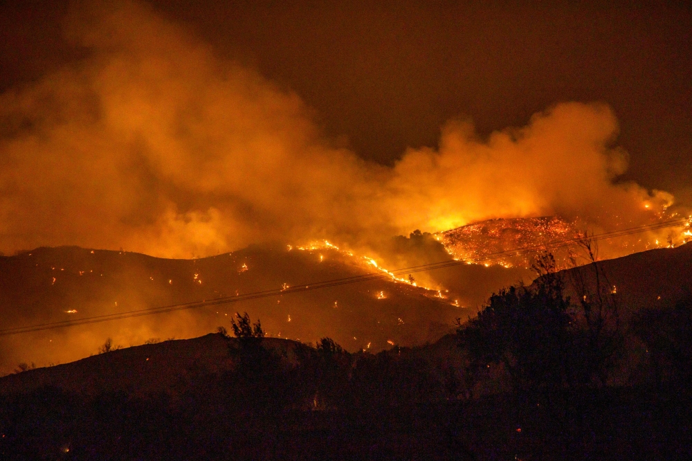 (Files) Trees burn in a forest on the slopes of the Troodos mountain chain, as a giant fire rages on the Mediterranean island of Cyprus, during the night of July 3, 2021. (Photo by Georgios Lefkou Papapetrou / AFP)
