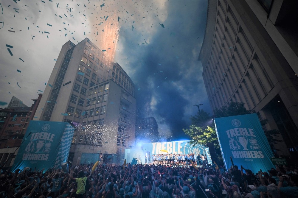 Manchester City's players celebrate on stage with their trophies following an open-top bus victory parade for their European Cup, FA Cup and Premier League victories, in Manchester, northern England on June 12, 2023. (Photo by Oli Scarff / AFP)