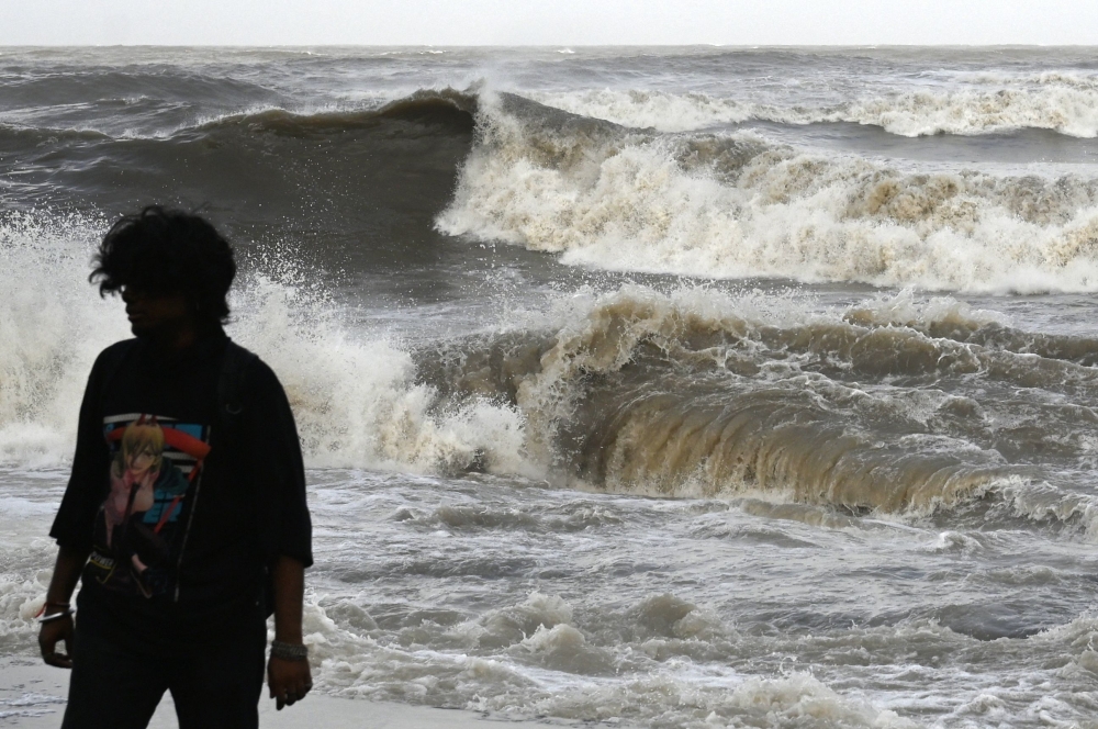 A man walks away from the seafront as high tidal waves hit the coast in Mumbai on June 13, 2023, as cyclone Biparjoy makes its way across the Arabian Sea towards the coastlines of India and Pakistan. (Photo by Punit Paranjpe / AFP)