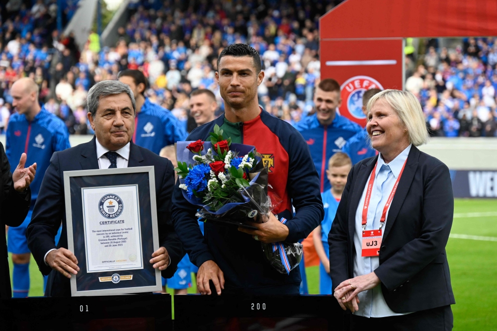 Portugal's forward Cristiano Ronaldo (C) is honoured with a certificate of the Guinness World Records for having achieved 200 goals within almost 20 years of his career, prior to the UEFA Euro 2024 group J qualification football match between Iceland and Portugal in Reykjavik on June 20, 2023. Photo by Halldor KOLBEINS / AFP