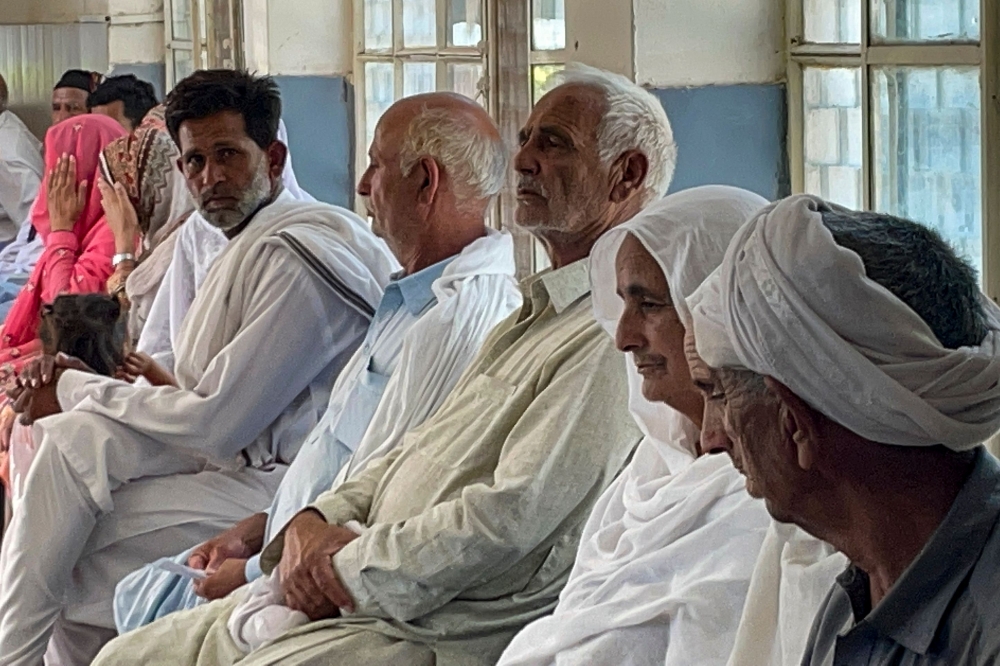 In this picture taken on June 20, 2023, relatives of migrants, who went missing after an overloaded trawler capsized and sank in the Ionian Sea, wait to provide DNA samples at a hospital in Bandli village, in Pakistan-administered Kashmir. (Photo by Sajjad QAYYUM / AFP)