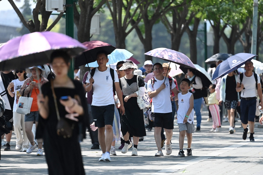 People shelter from the sun under umbrellas after visiting the Forbidden City during a heatwave in Beijing on June 24, 2023. Photo by GREG BAKER / AFP