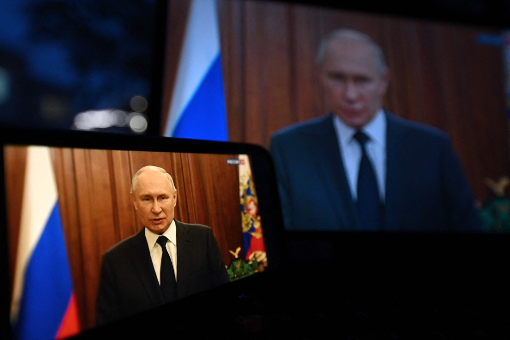 This photograph shows Russia's President Vladimir Putin, seen on a smartphone screen and a laptop screen, making a statement in Moscow, on June 26, 2023. (Photo by NATALIA KOLESNIKOVA / AFP)
