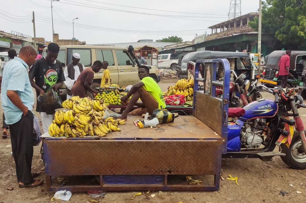 People buy fruits from a street vendor at a market in Gadaref city in war-torn Sudan on July 2, 2023. (Photo by AFP)