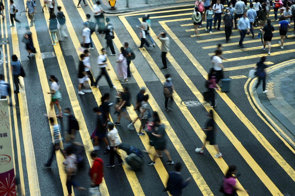 People cross a road in Central, a financial hub in Hong Kong on July 3, 2023. (Photo by May James / AFP)