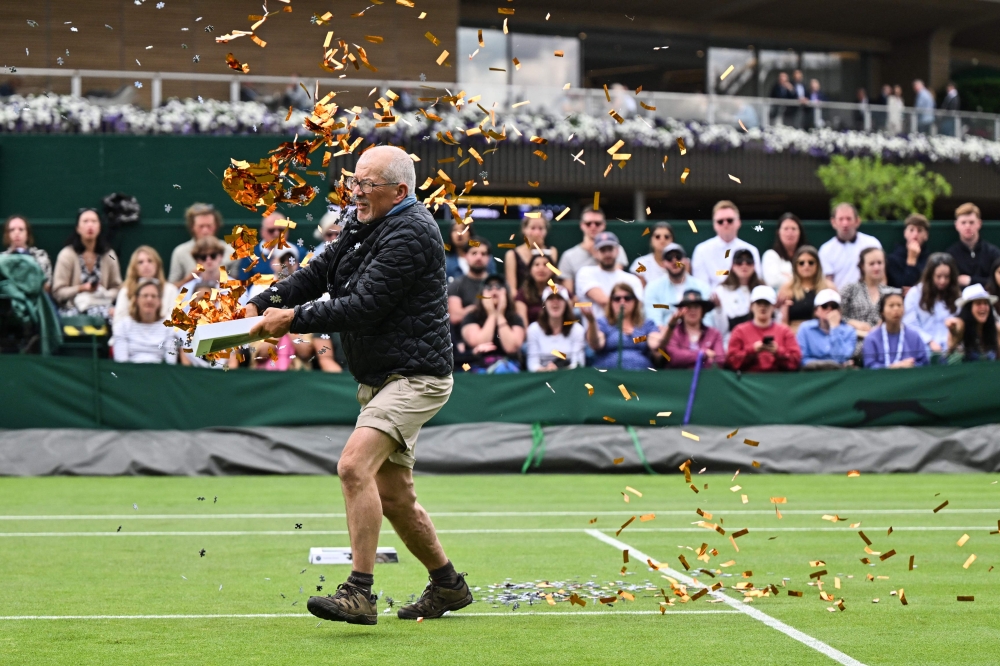 A Just Stop Oil demonstrator throws orange confetti on court 18 as he disrupts the women's singles tennis match between Australia's Daria Saville and Britain's Katie Boulter on the third day of the 2023 Wimbledon Championships at The All England Tennis Club in Wimbledon, southwest London, on July 5, 2023. (Photo by Glyn KIRK / AFP)
