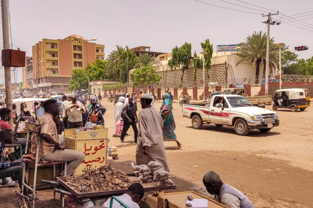 Pedestrians and vehicles move along a road outside a branch of the Central Bank of Sudan in the country's eastern city of Gedaref on July 9, 2023. (Photo by AFP)