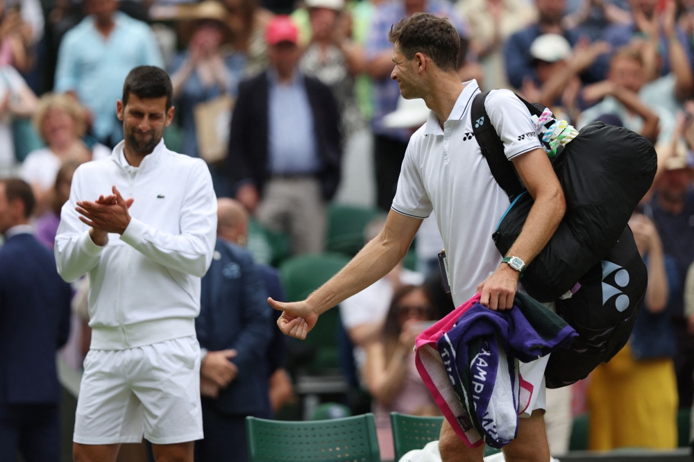 Poland's Hubert Hurkacz gives a thumbs-up to Serbia's Novak Djokovic after being defeated during their men's singles tennis match on the eighth day of the 2023 Wimbledon Championships at The All England Tennis Club in Wimbledon, southwest London, on July 10, 2023. (Photo by Adrian DENNIS / AFP)