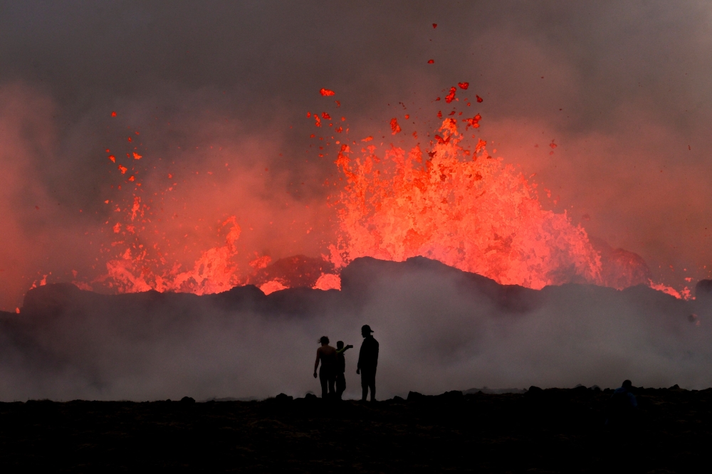 People watch flowing lava during an volcanic eruption near Litli Hrutur, south-west of Reykjavik in Iceland on July 10, 2023. Photo by Kristinn Magnusson / AFP