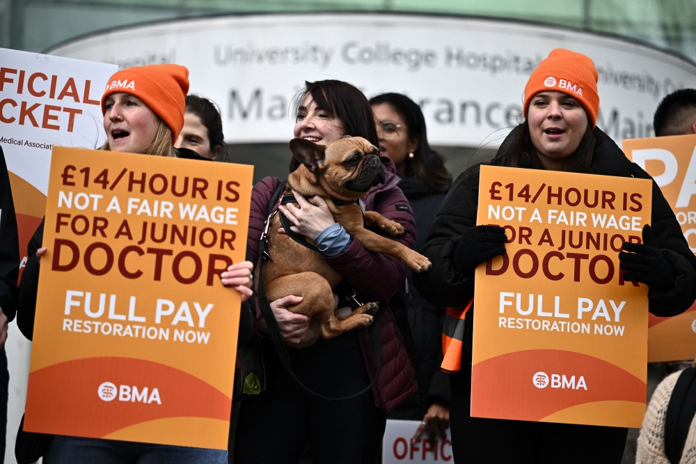 People hold British Medical Association (BMA) branded placards calling for better pay, as they stand on a picket line outside University College Hospital (UCH) in central London on April 12, 2023, during a strike by junior doctors -- physicians who are not senior specialists but who may still years of experience. 
