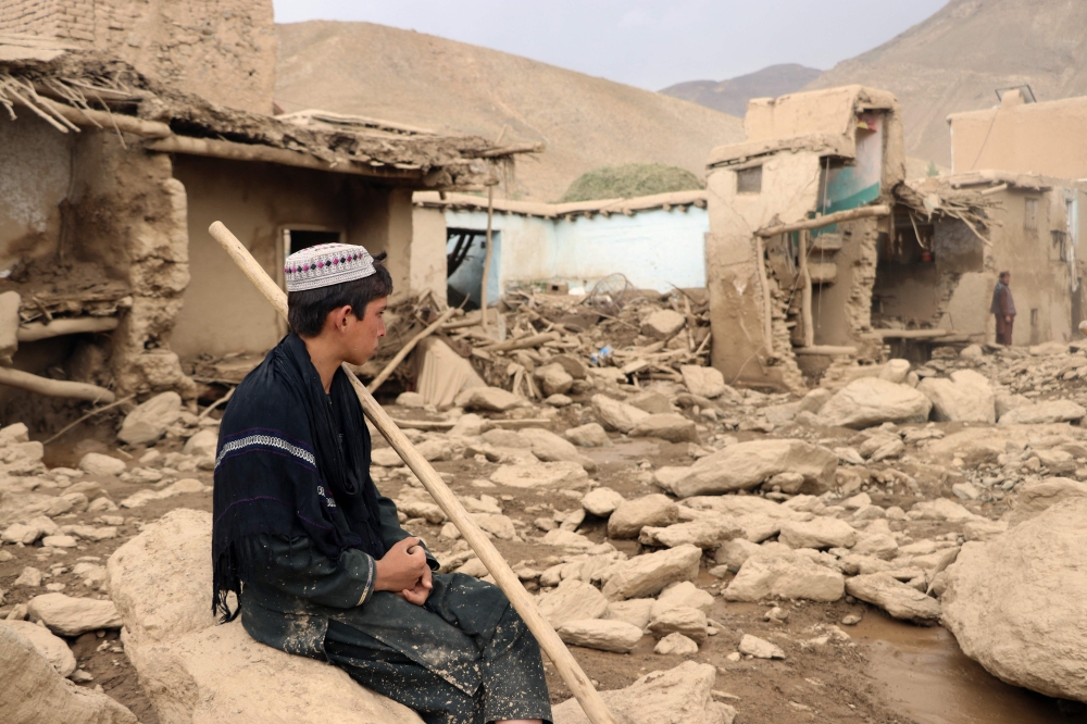 An Afghan resident sits next to his house that was damaged in flash floods in the Jalrez district of Maidan Wardak province on July 23, 2023. (Photo by AFP)
