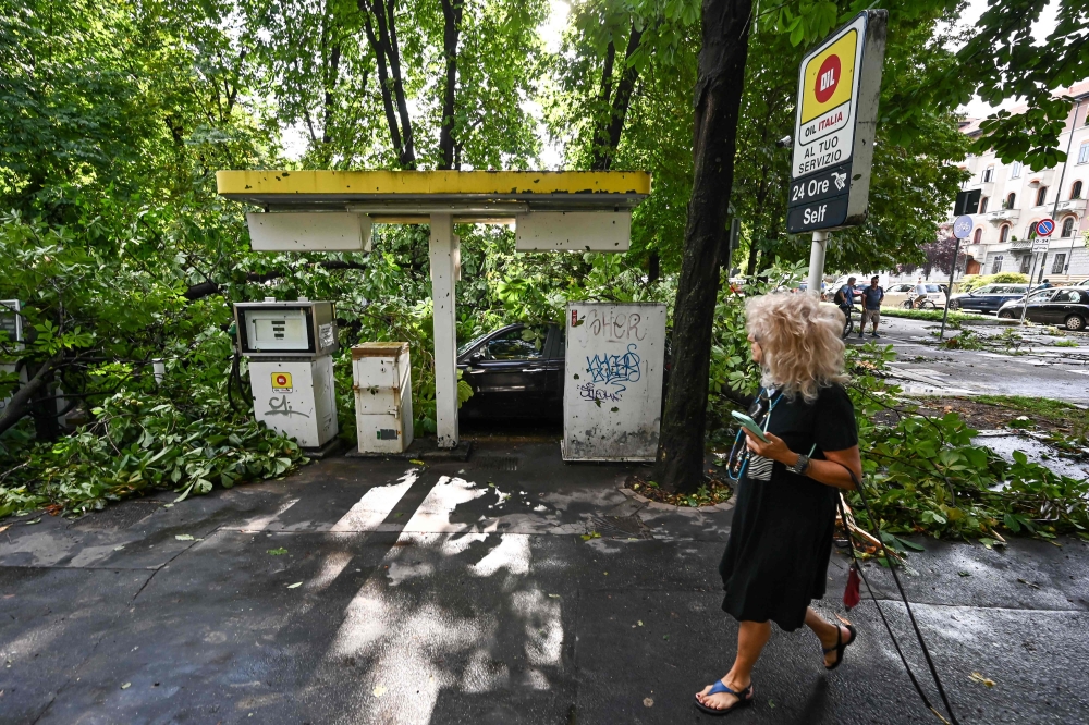 Fallen tree branches cover a gas station in Milan on July 25, 2023 after an overnight rainstorm hit the city. (Photo by Piero Cruciatti / AFP)