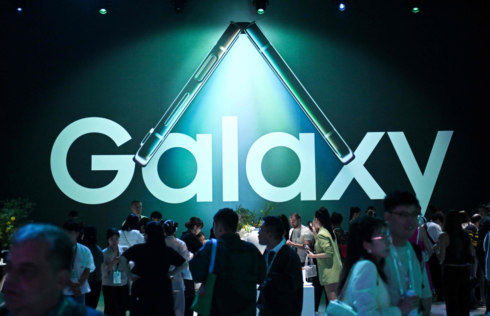 Attendees walk past the logo of Samsung Galaxy during the Samsung Galaxy Unpacked 2023 event in Seoul on July 26, 2023. (Photo by Jung Yeon-je / AFP)