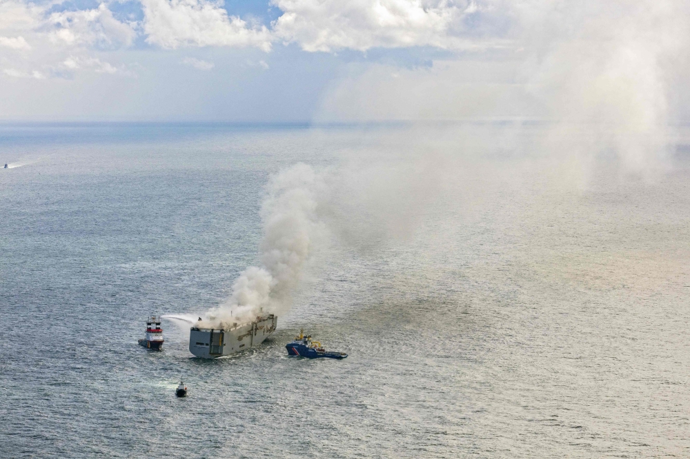 An aerial photograph of emergency boats extinguishing a fire aboard the Panamanian-registered car carrier cargo ship Fremantle Highway. Photo by Flying Focus / ANP / AFP